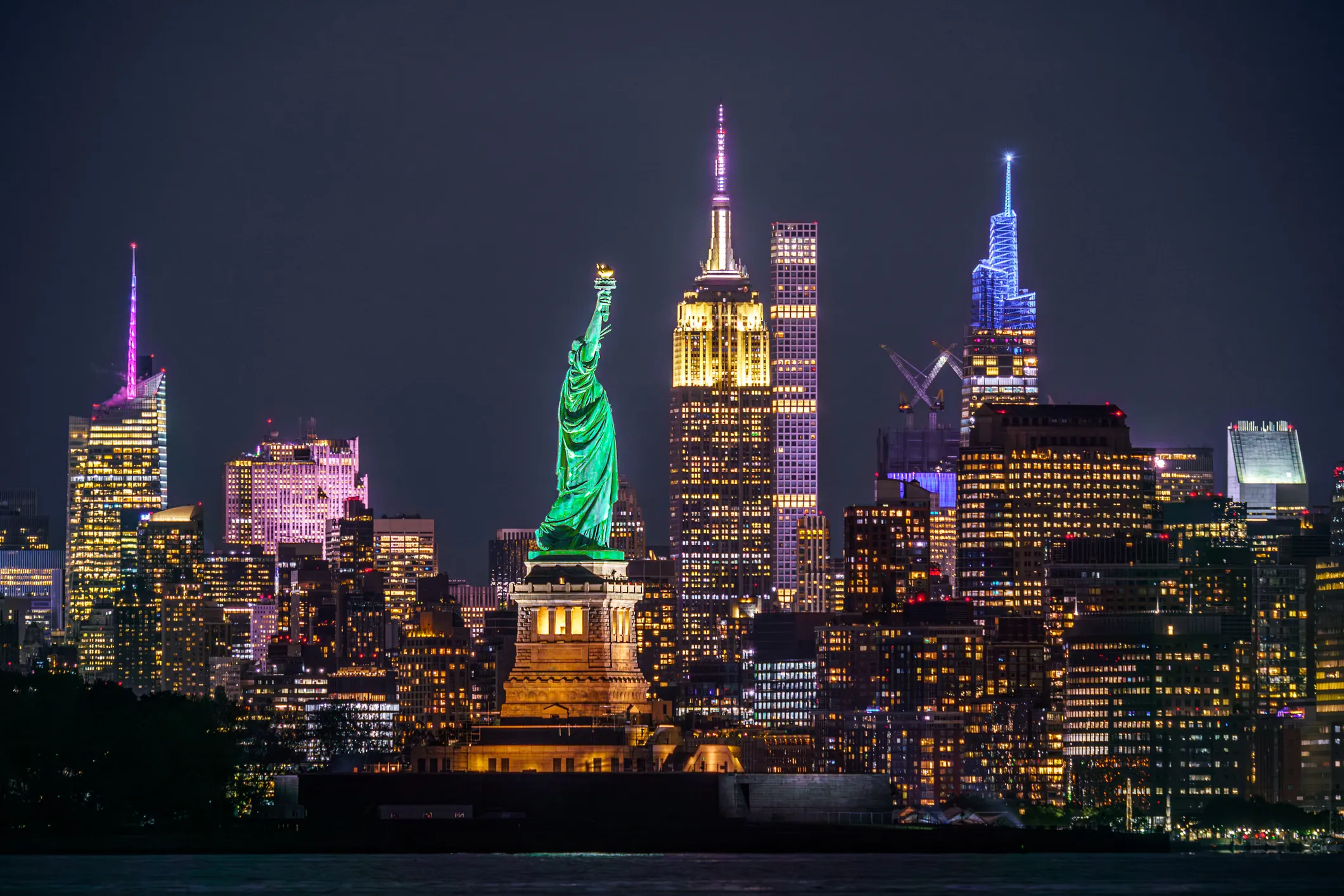 Statue of Liberty and illuminated New York City landmarks